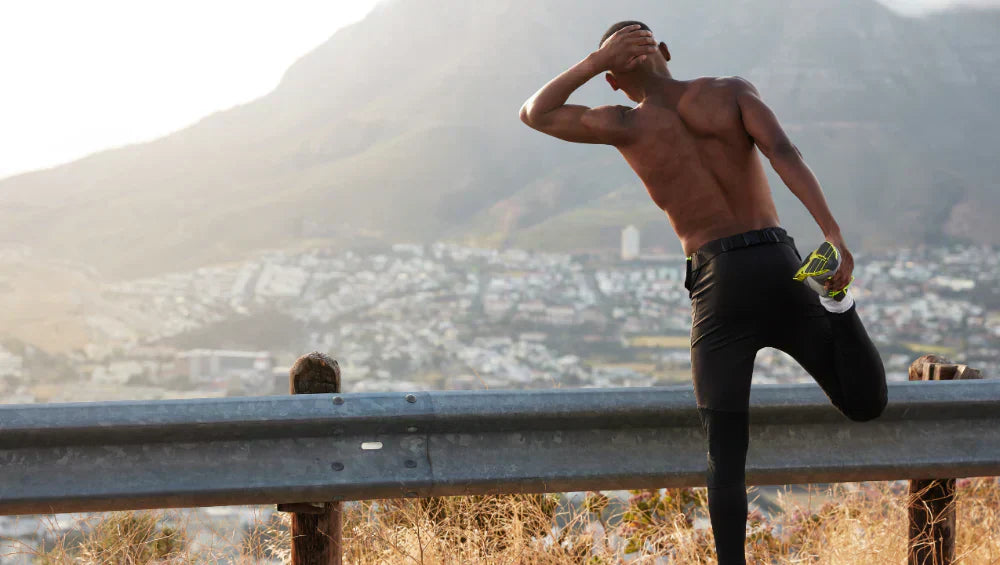 Homme en train de s'étirer sur le bord du route en pleine montagne