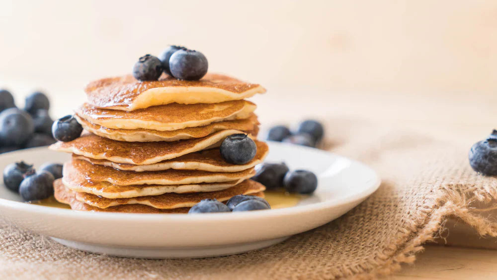Plusieurs pancake protéiné dans une assiette sur un table servis avec plusieurs baie