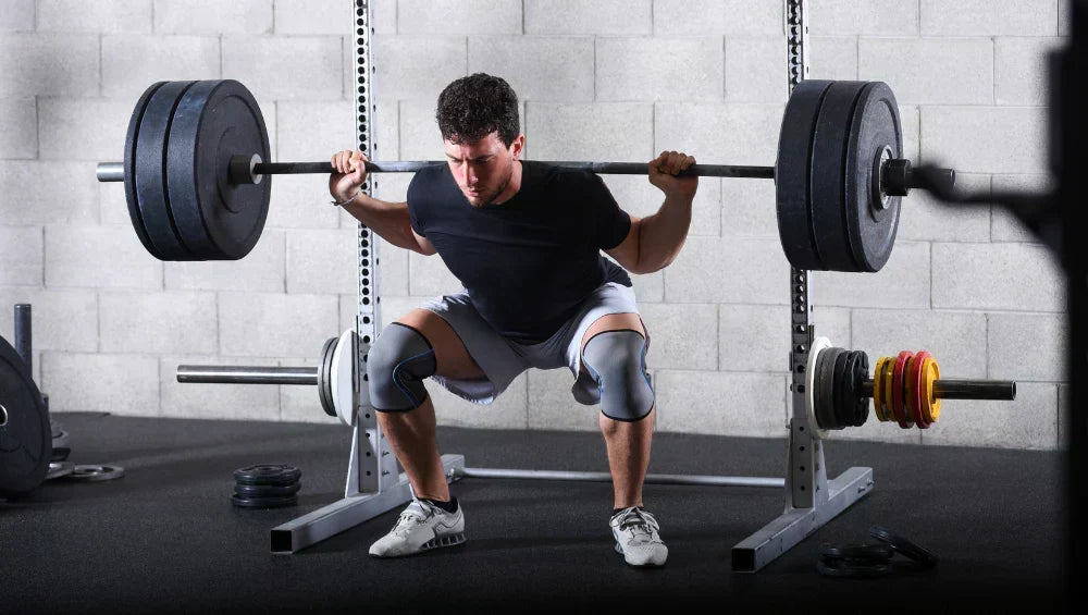Homme en train d'effectuer une serie de squat libre a la barre olympique dans une salle de gym