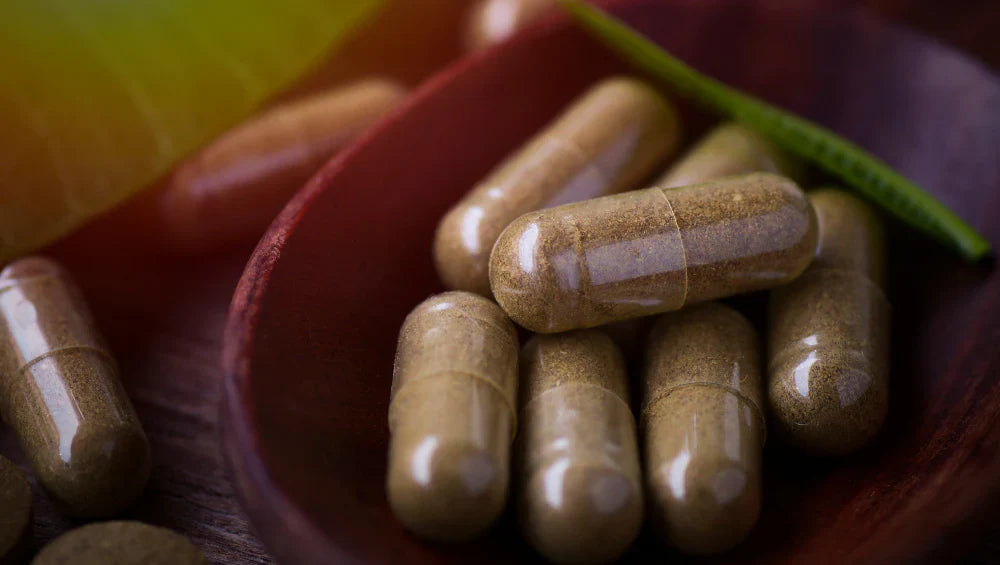 Plusieurs pilules d'ashwagandha dans une cuillère en bois