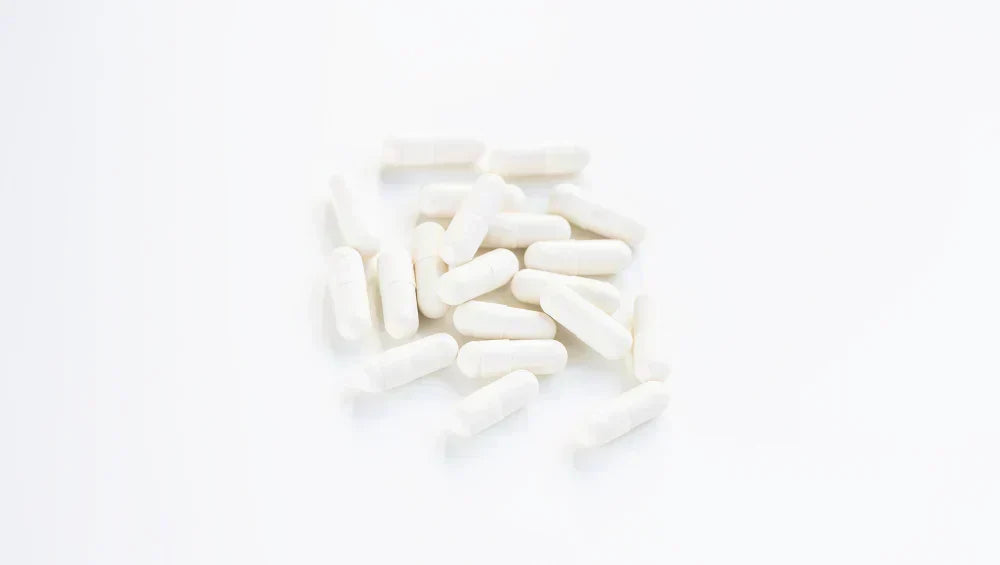 Plusieurs pilules blanche sur un fond blanc vu d'en haut