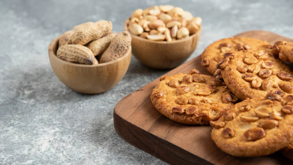 Plusieurs cookie garnis de cacahuète avec des bols en fonds de cacahuètes