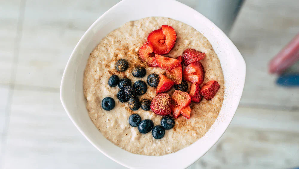 Un bol contenant du porridge avec des fraise et myrtille sur le haut du porridge
