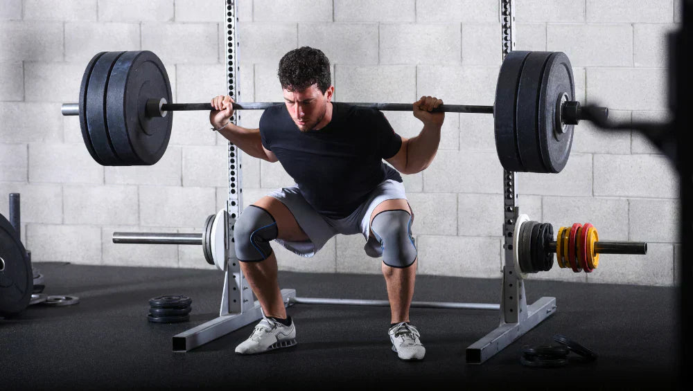 Homme en train d'effectuer une serie de squat libre a la barre olympique dans une salle de gym